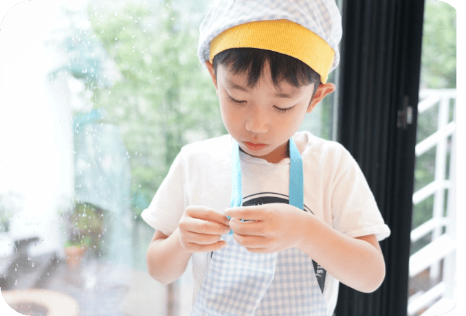 エプロンを自分でつける子ども